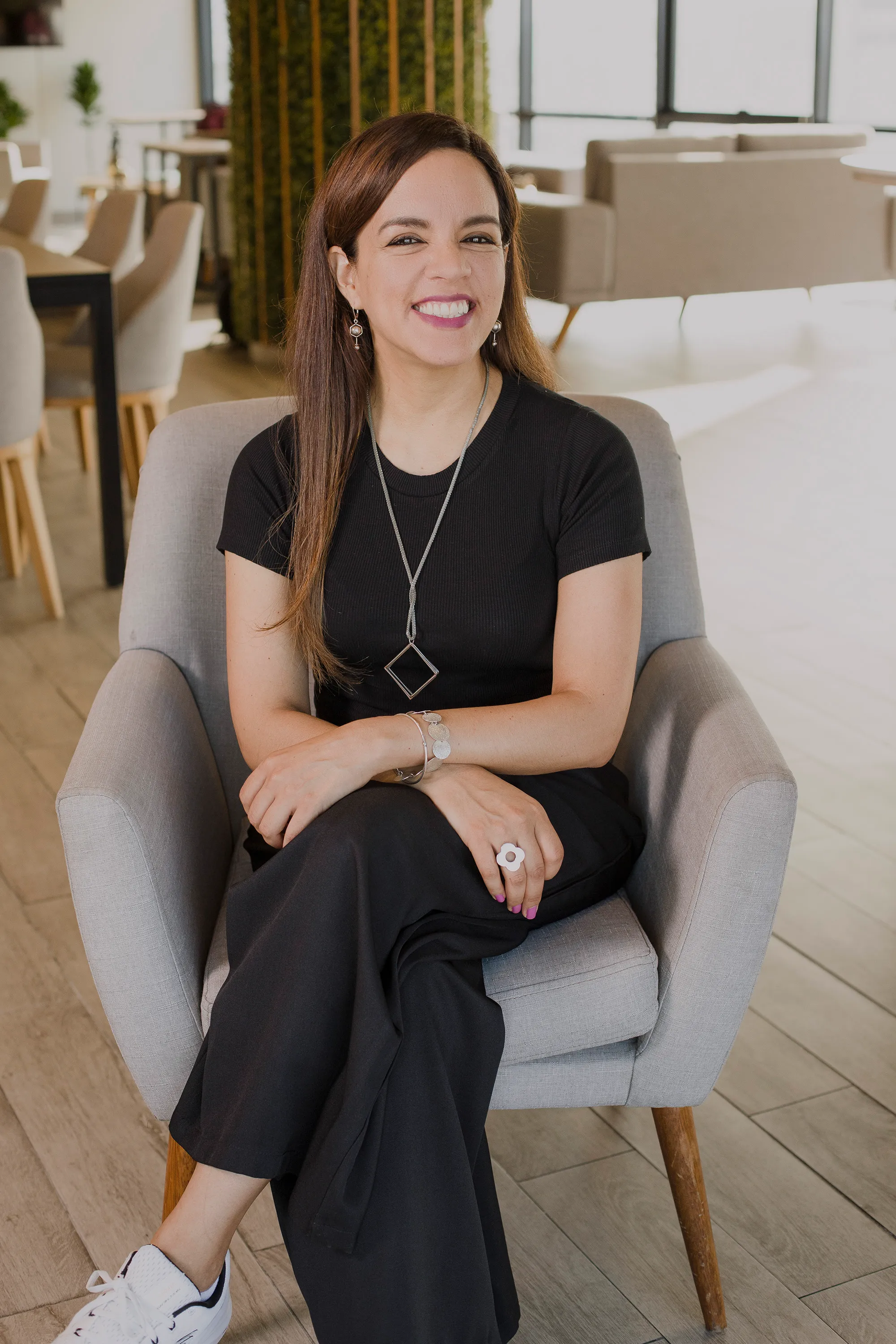 Alexandra Oporto sitting in a grey armchair